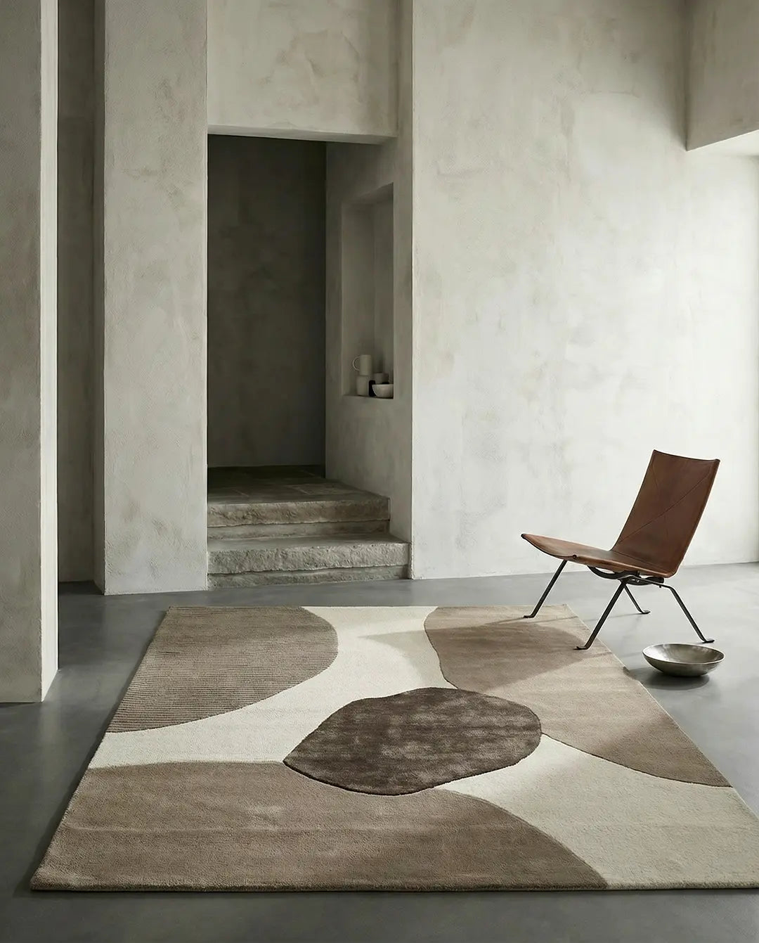 Modern abstract area rug with textured brown and beige organic shapes in a minimalist living room.