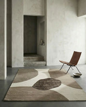 Modern abstract area rug with textured brown and beige organic shapes in a minimalist living room.