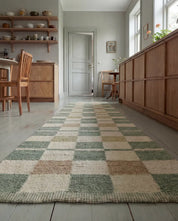 Langer Flurläufer mit kariertem Muster in Salbeigrün und Beige auf einem Holzfußboden in einem hellen Wohnraum.