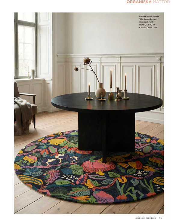 Pressbild från magasinet Hus & Hem med den runda mattan Heritage Garden Charcoal Multi från Classic Collection, med organiskt botaniskt mönster i flerfärgade toner under ett runt svart matbord.