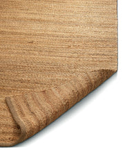 Närbild av en beige matta av naturfärgad jutefiber med grov vävd struktur. Matta Jute Plain - Classic Collection
