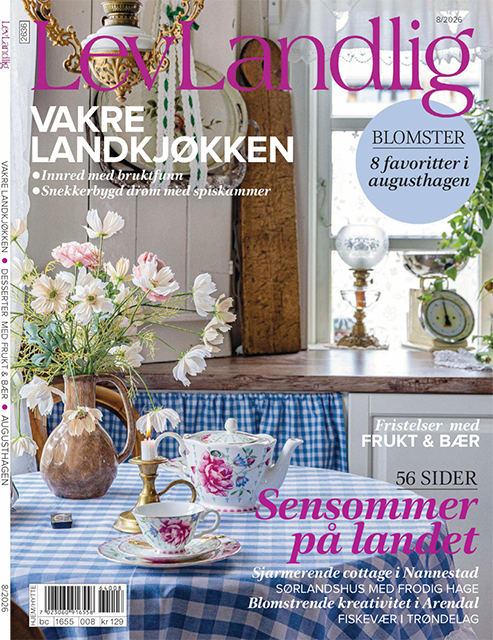 Omslag till magasinet Lev Landlig, augusti 2026, med somrig lantlig interiör, blommor och dukat bord i blå och vita toner.