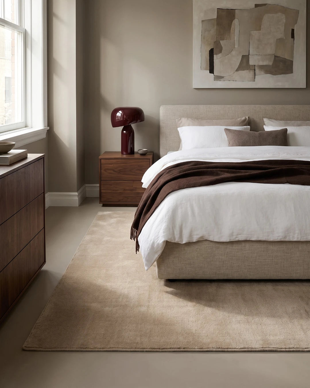 Handvävd ullmatta Lodge i färgen Natural Beige från Classic Collection, placerad under en säng i ett lugnt sovrum med varma, neutrala toner.