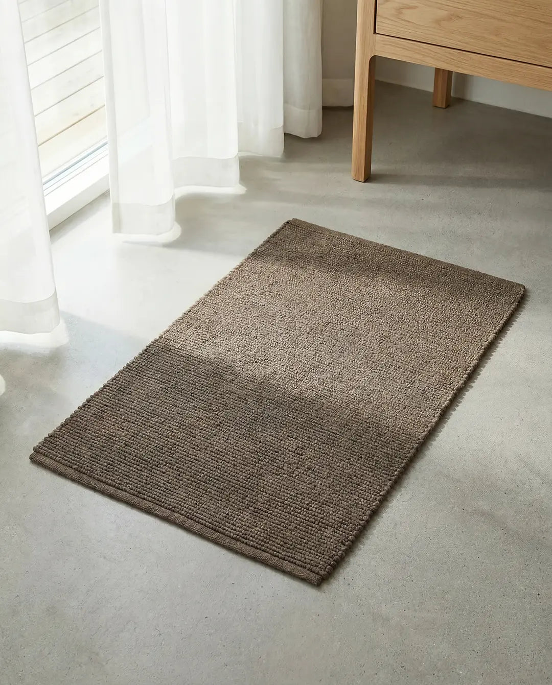Handvävd dörrmatta Merino Brun från Classic Collection i ull, placerad på ett ljust golv intill ett fönster.