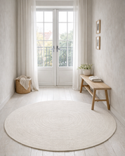 Vit rund ullmatta Merino placerad i ett ljust rum med trägolv, dörrar i glas och enkel träbänk