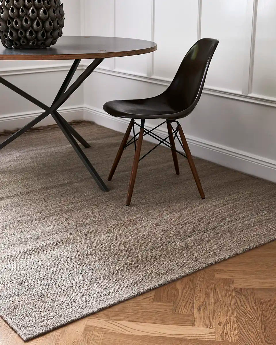 Flatvävd ullmatta Plain i naturbeige placerad under matbord i klassisk interiör med fiskbensparkett