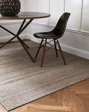 Flatvävd ullmatta Plain i naturbeige placerad under matbord i klassisk interiör med fiskbensparkett