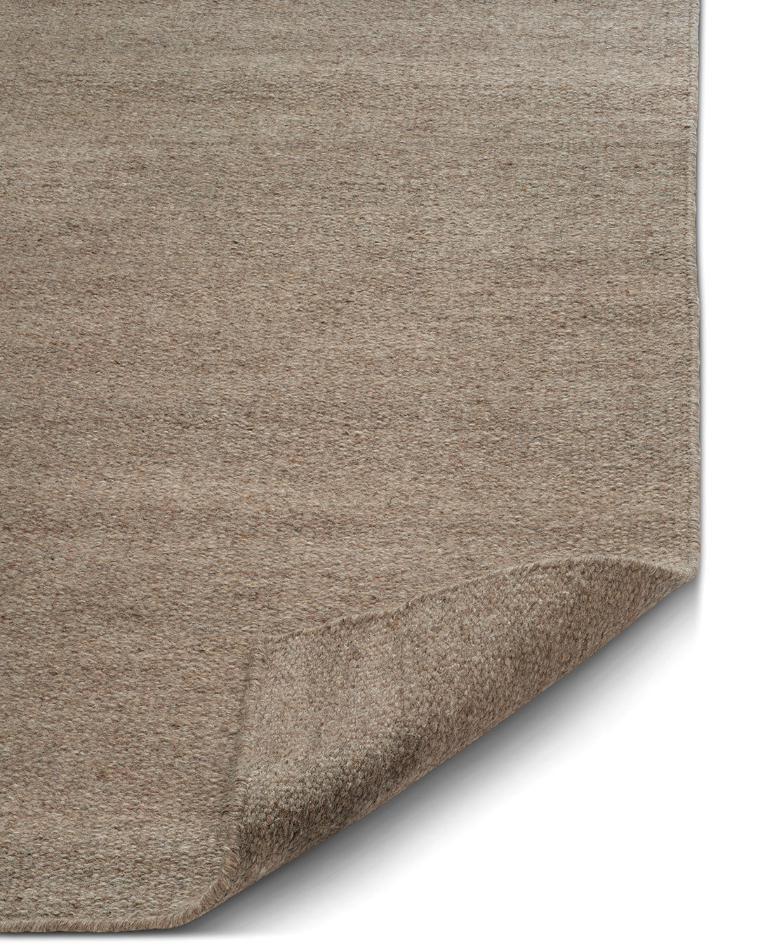 Detaljbild av flatvävd ullmatta Plain i naturbeige som visar tät vävstruktur och rak kant