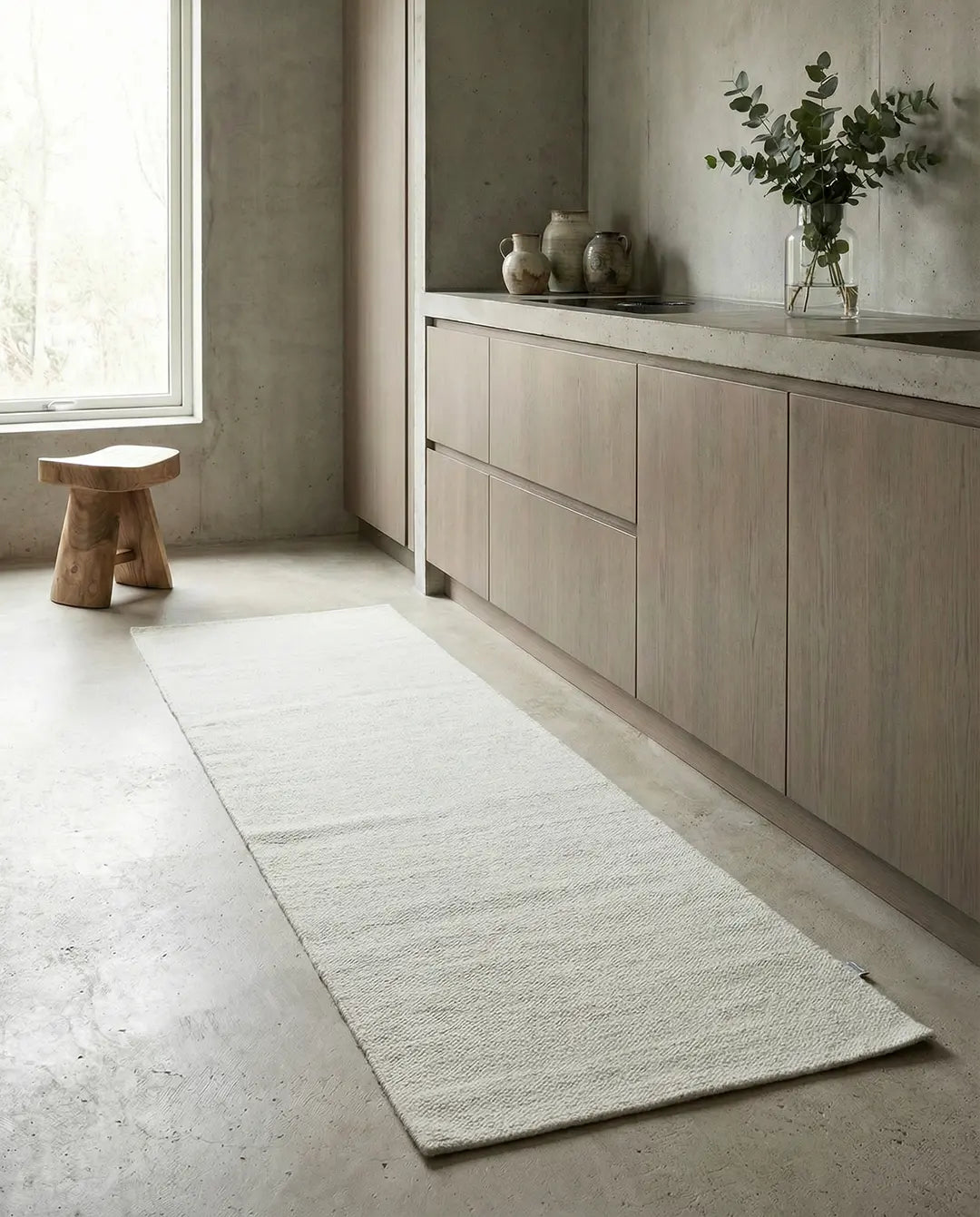 Minimalist white textured runner rug on a concrete kitchen floor in a modern interior.