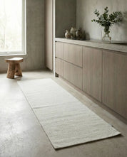 Minimalist white textured runner rug on a concrete kitchen floor in a modern interior.