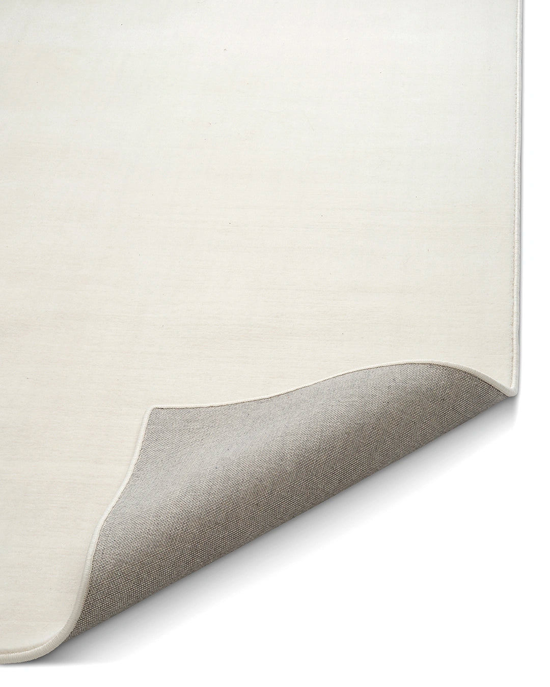 Närbild av ullmatta Lobby Off-white från Classic Collection med uppvikt hörn som visar mattans undersida, kantavslut och täta väv.