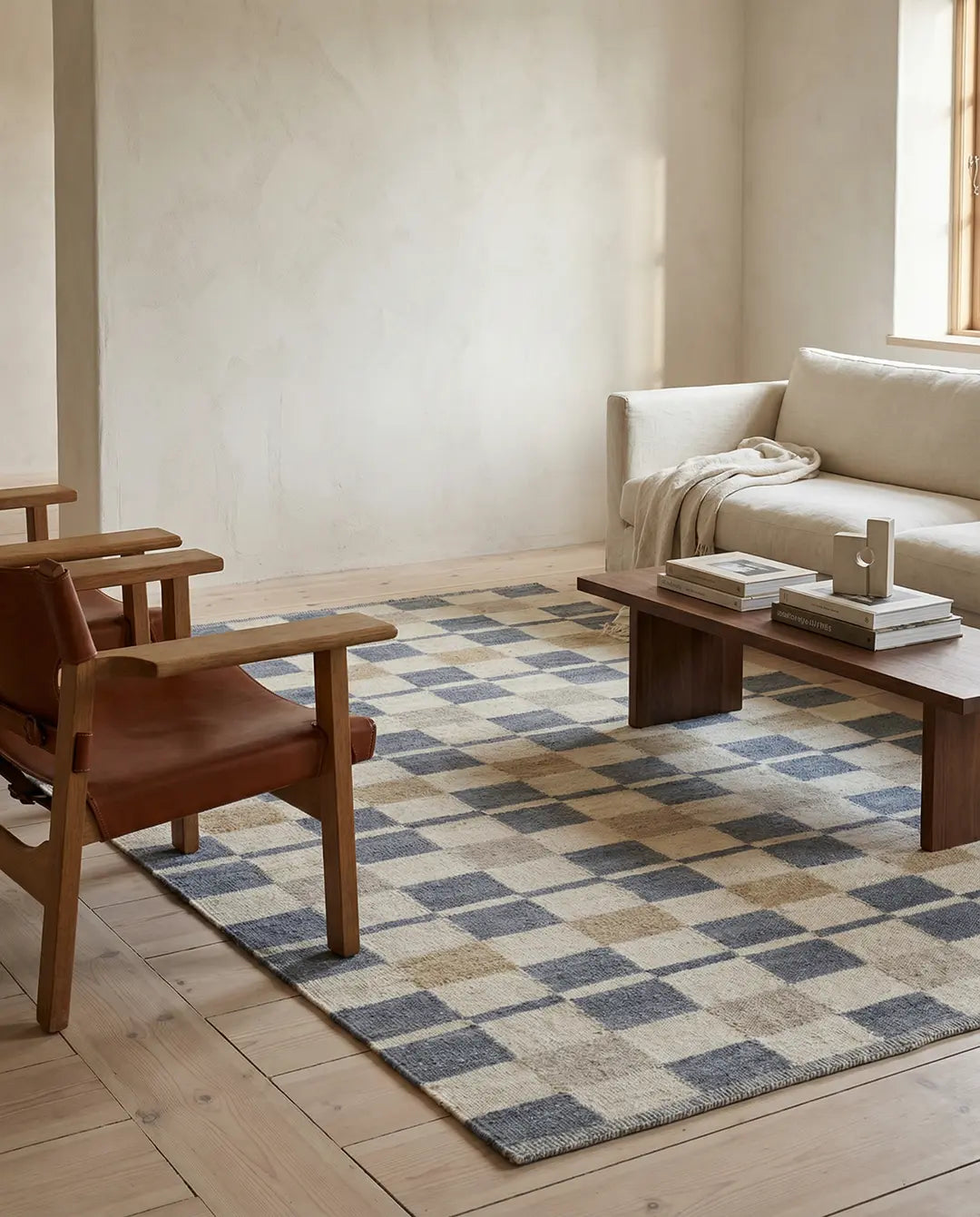 Rutig matta i blått, beige och grått i ett modernt vardagsrum med trämöbler och en beige soffa.