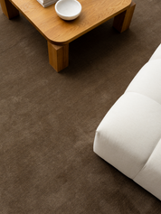 Brun matta i modellen Solid Brun under ett soffbord i trä och en ljus soffa.