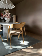 Handvävd ullmatta Solid Blå under matbord i marmor med trästolar, i rum med varm belysning och harmoniska bruna väggar.