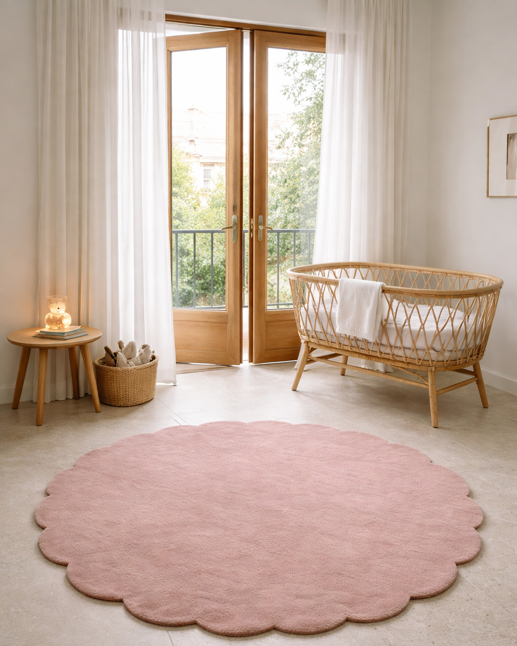 Rosa ullmatta i modellen Shell, rund med mjukt vågformad kant, placerad i ett ljust barnrum med spjälsäng.