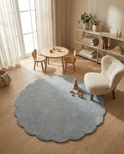 Runder, hellblauer Teppich mit gewelltem Rand in einem modern eingerichteten Kinderzimmer.