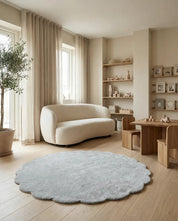 Runder, hellgrauer Teppich mit Blütenrand in einem hellen, skandinavisch eingerichteten Wohn- oder Kinderzimmer.