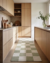 Moderner Küchenläufer mit grün-weißem Schachbrettmuster in einer minimalistischen Holzküche.