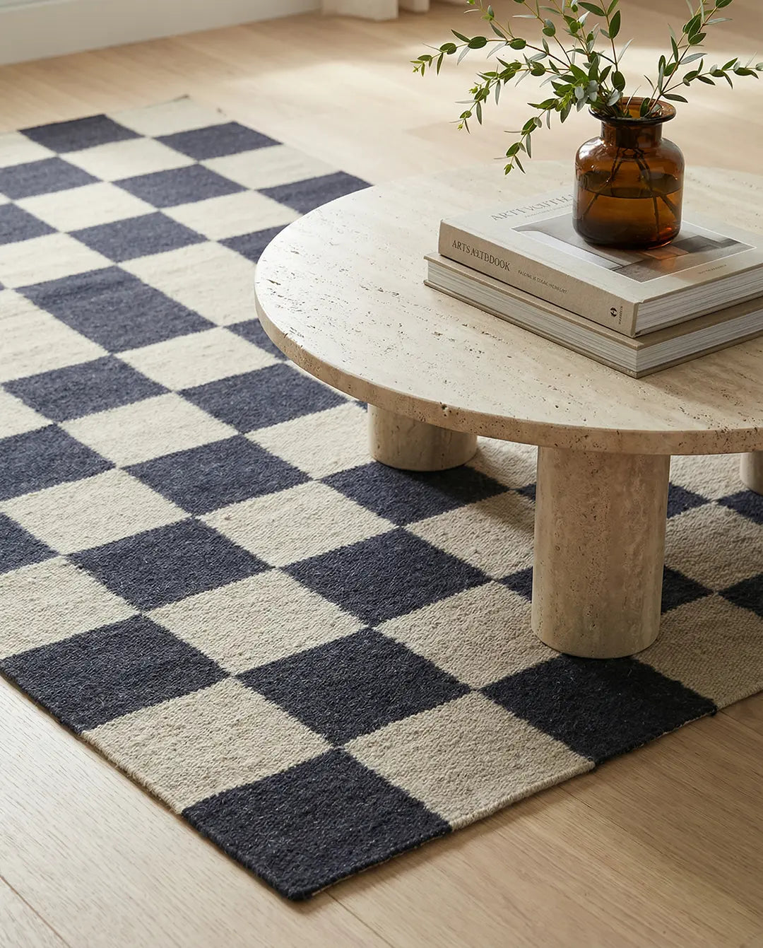 Moderner Webteppich mit schwarz-beigem Schachbrettmuster in einem hellen Wohnraum.