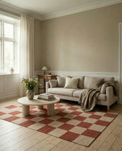 Beiges Sofa mit Kissen und kariertem Teppich in Terrakotta und Creme in einem gemütlichen, modernen Wohnzimmer.