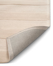 Närbild av beige Stripe Bouclé-matta med randig struktur och uppvikt hörn som visar mattans vävda baksida.