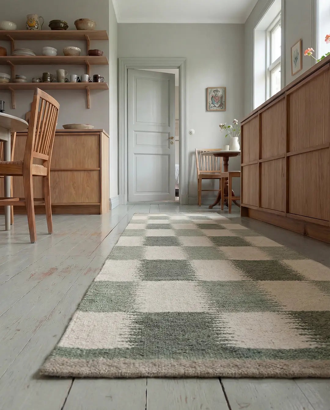 Rektangulär matta med rutigt mönster i grönt och vitt på trägolv i ett ljust kök.