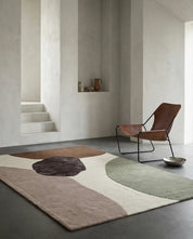 Moderner Teppich mit organischen, geometrischen Formen in Braun-, Beige- und Grüntönen in minimalistischem Interieur.