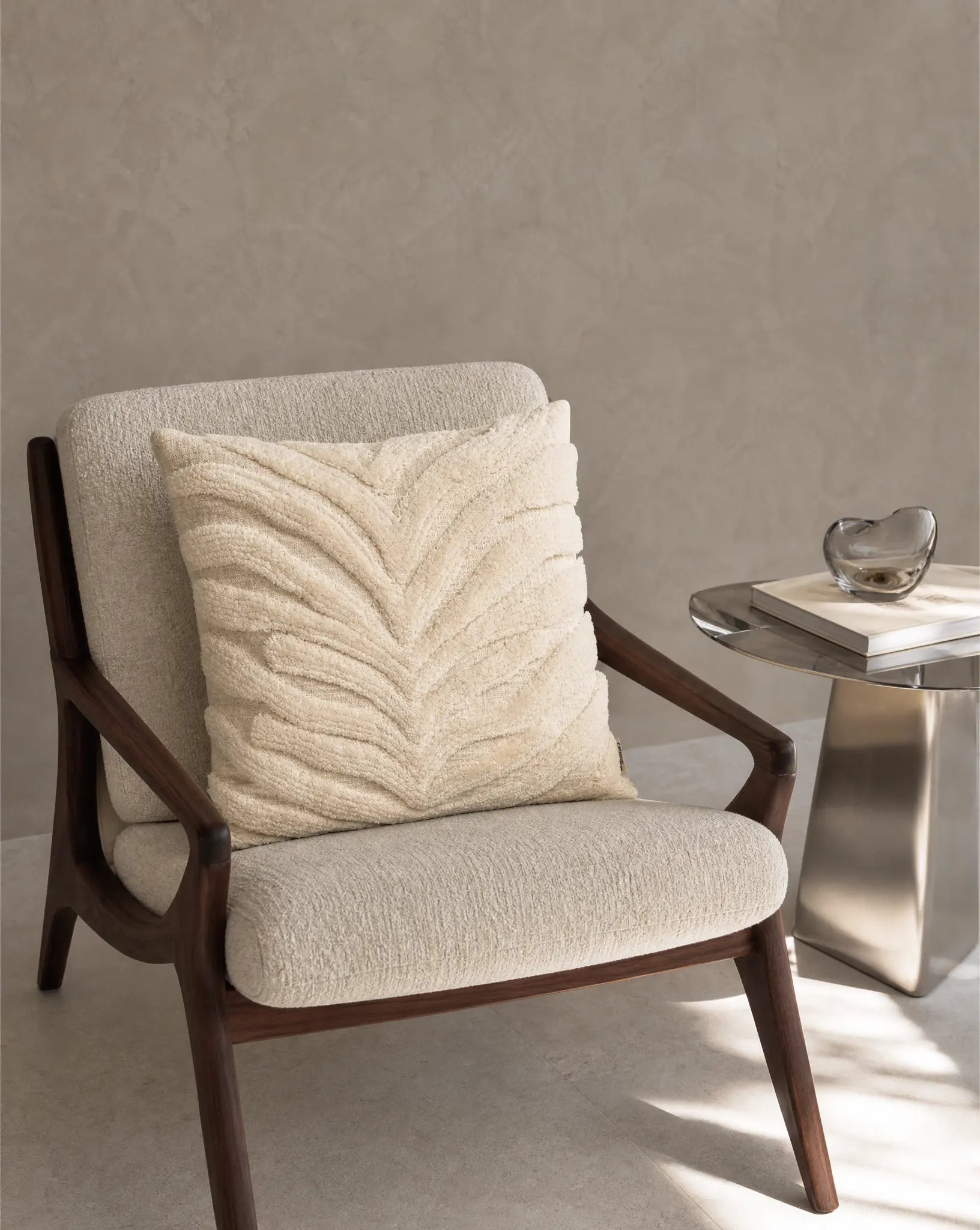 Kuddfodral Classic Zebra Tuft 50x50 cm från Classic Collection i enfärgat bomull med taktilt mönster, stylat i en ljus fåtölj i en varm, neutral interiör.