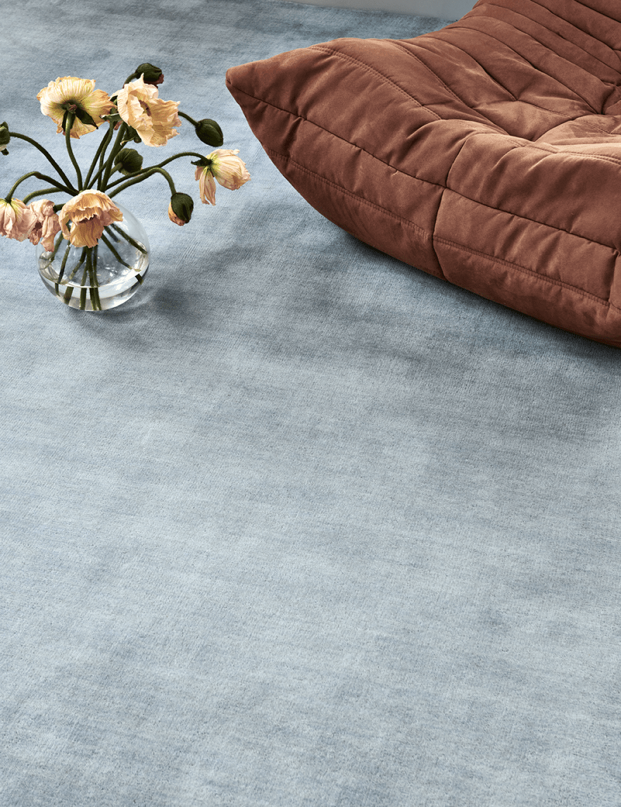 Handvävd ullmatta Solid Blå vid fåtölj i terrakotta, i rum med mycket dagsljus och blommor i coral-färg.