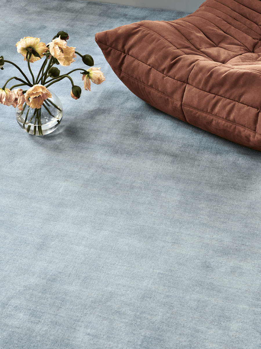 Handvävd ullmatta Solid Blå vid fåtölj i terrakotta, i rum med mycket dagsljus och blommor i coral-färg.