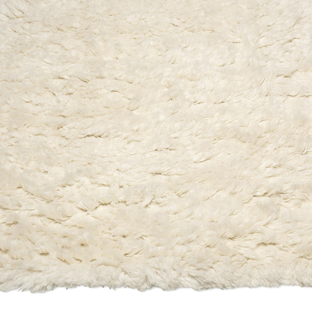 Close-up of a plush, cream-colored shag area rug with a soft, deep-pile wool texture.