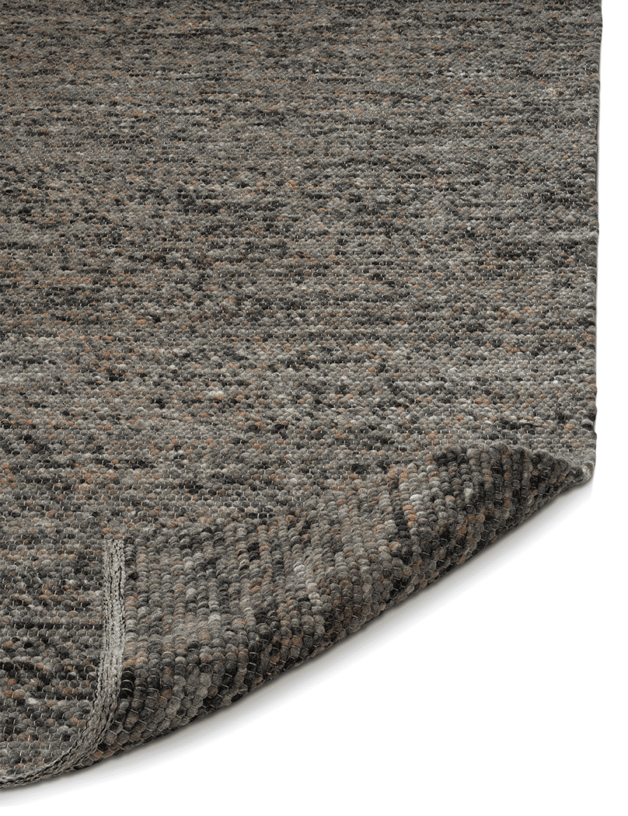 Textured dark grey wool area rug with a chunky looped pile and a corner folded over to show the durable weave.