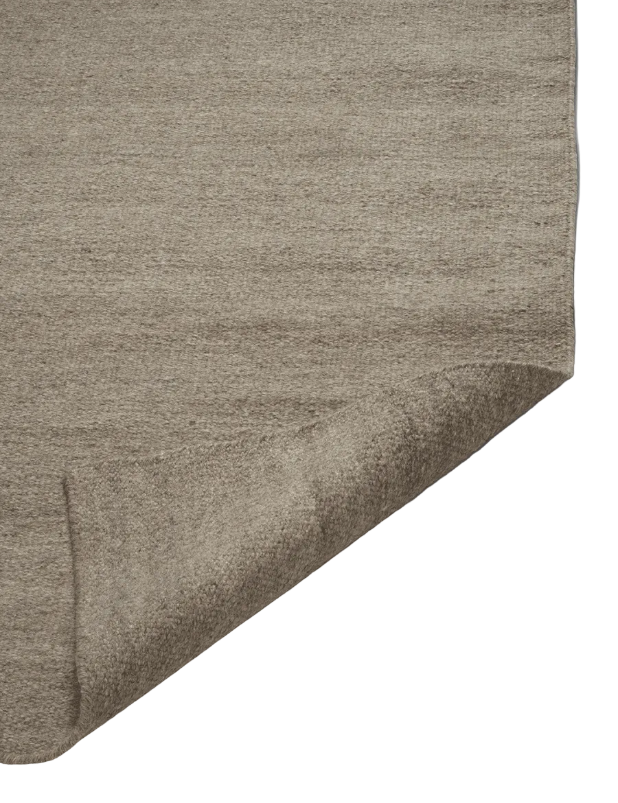 Detaljbild av flatvävd ullgångmatta Plain i naturbeige som visar tät vävstruktur och rak kant