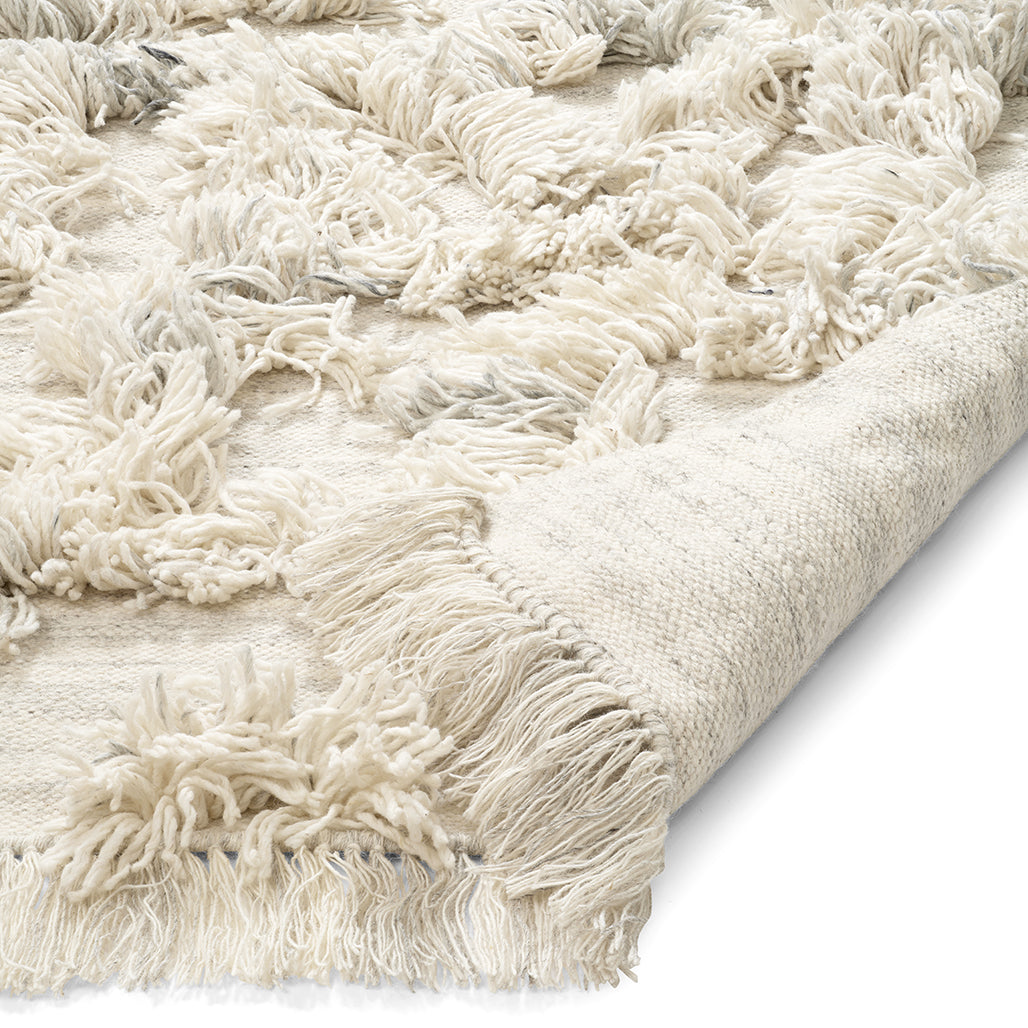 Cream-colored Moroccan shag area rug with textured diamond pattern, fringe edges, and soft pile material.