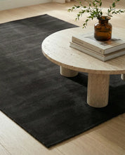 Mjuk, enfärgad mörkgrå matta i rektangulär form på ett ljust trägolv.