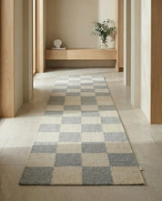 Langer Flurläufer mit grau-weißem Schachbrettmuster in einem modernen, minimalistischen Wohnflur.