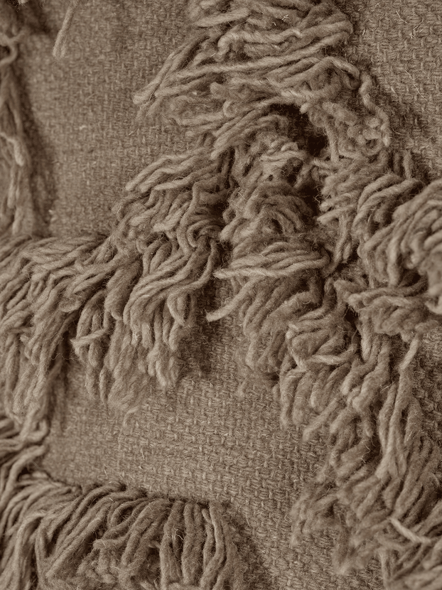 Detaljbild av Rio Beige väggbonad i handvävd ull som visar tuftat mönster och vävd botten