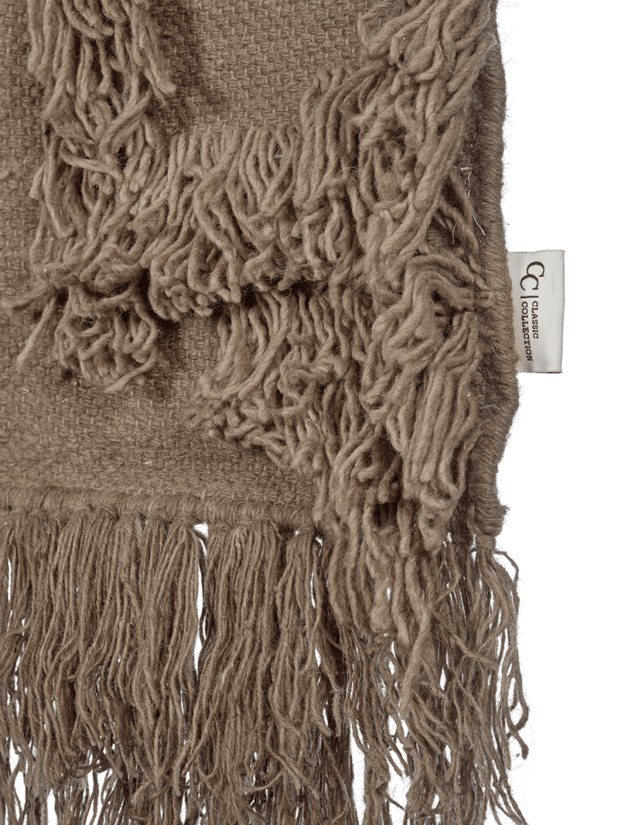 Detaljbild av Rio Beige väggbonad i ull med fransar, vävd kant och Classic Collection-etikett