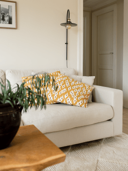 Kuddfodral Ikat Diamond Ockra och Ikat Block Ockra i bomull, 50x50 cm, placerade i en ljus soffa i vardagsrum med vägglampa och 